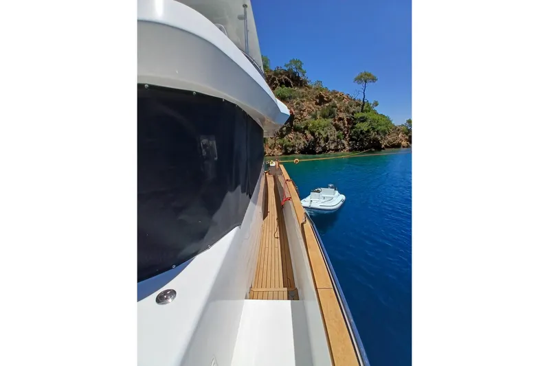  Yacht Photos Pics Side view of 2022 Sirena 58 yacht docked near lush coastline.