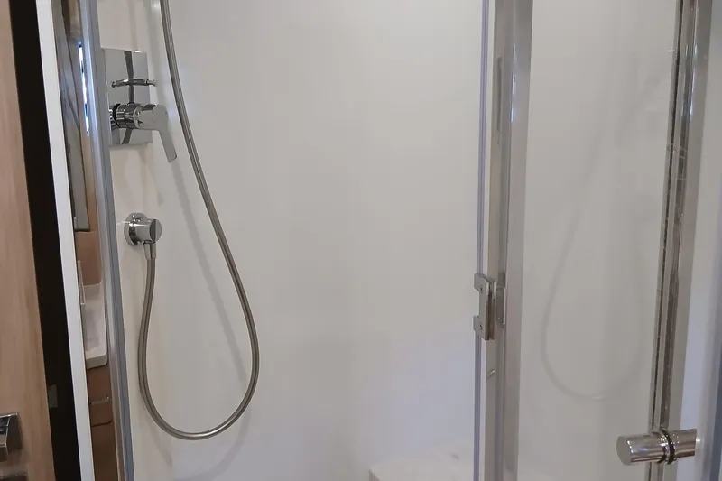  Yacht Photos Pics Modern shower area with glass door and chrome fixtures in a 2022 Sirena 58 yacht.