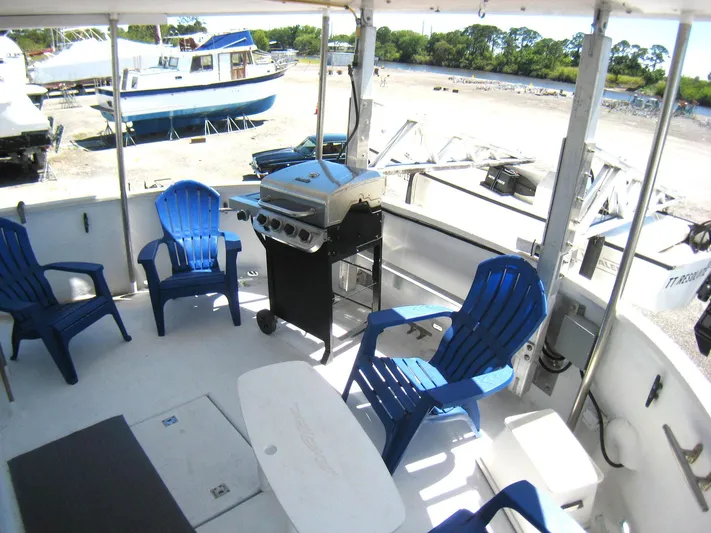 Resolute Yacht Photos Pics Outdoor deck of 1987 Custom Pilgrim Tribute boat with blue chairs and a grill.