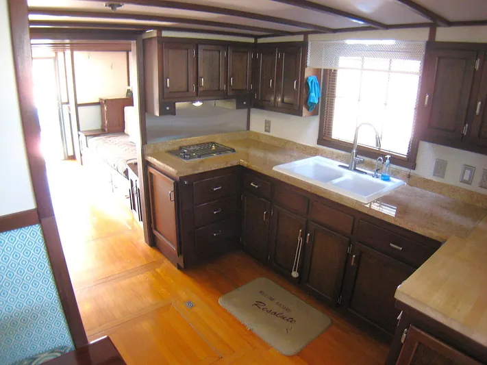 Resolute Yacht Photos Pics 1987 Custom Pilgrim Tribute kitchen with dark wood cabinets, dual sink, and stove.