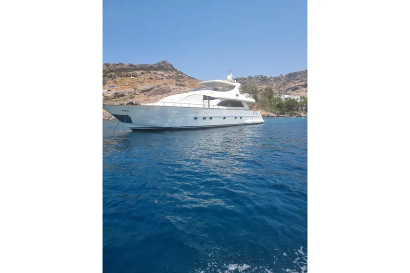  Yacht Photos Pics Luxurious 2011 Falcon 90 yacht anchored in clear blue waters near rocky coastline.