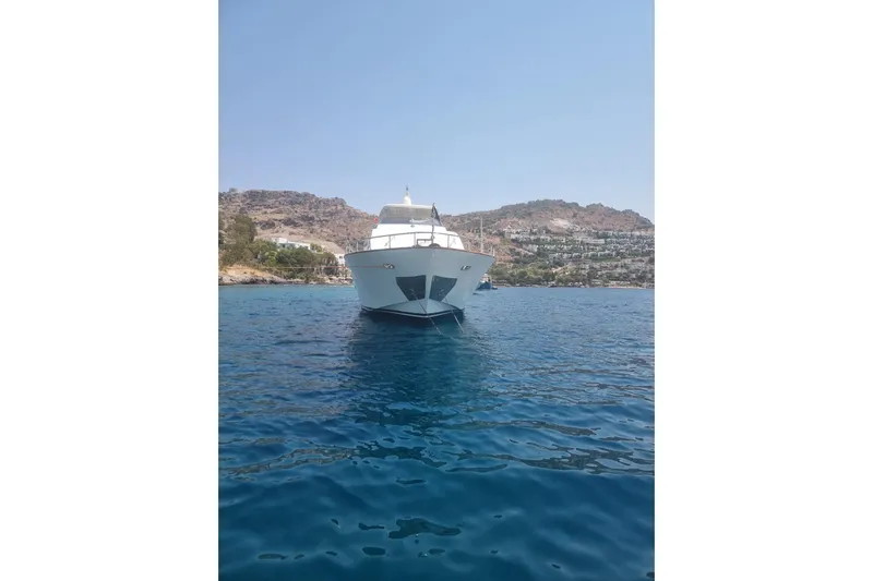  Yacht Photos Pics Luxury Falcon 90 yacht from 2011 on serene blue waters, with scenic coastal backdrop.