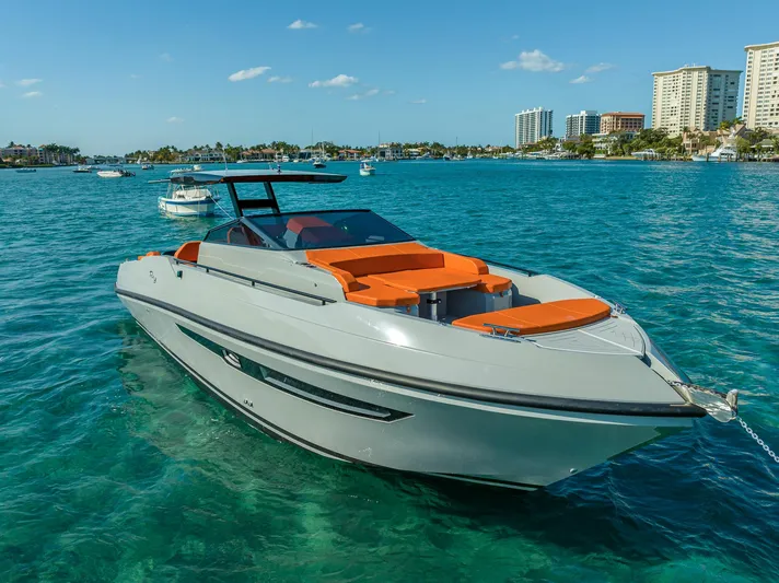  Yacht Photos Pics 2024 Rio Yachts Daytona 35 cruising on clear blue water near a city skyline.