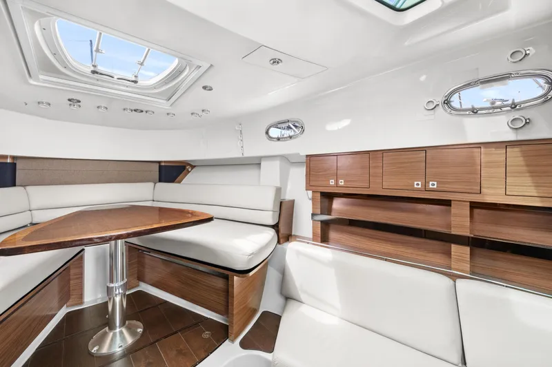  Yacht Photos Pics 2017 Boston Whaler 345 Conquest Pilothouse interior with white seating and wooden cabinetry.