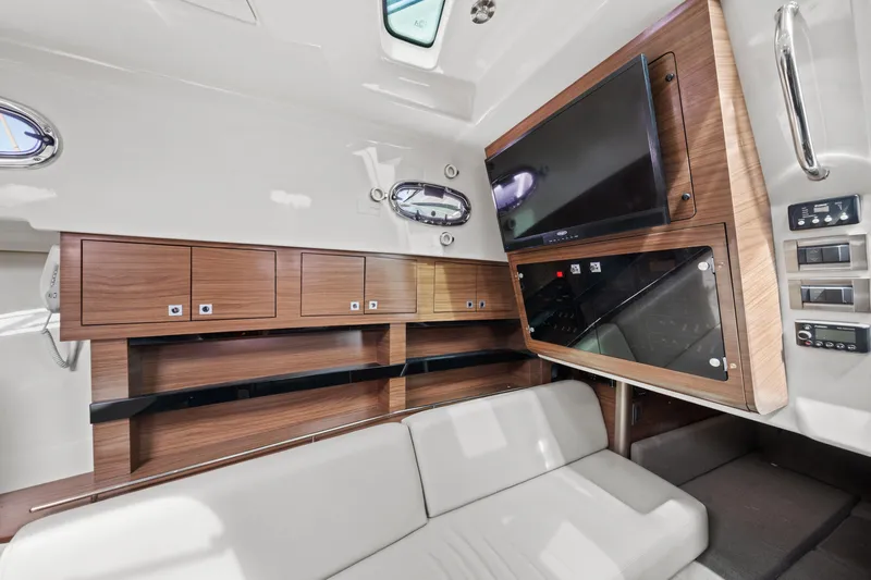  Yacht Photos Pics 2017 Boston Whaler 345 Conquest Pilothouse interior with TV, wooden cabinets, and white seating.
