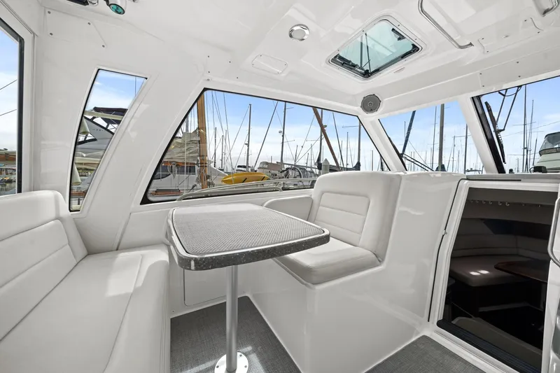  Yacht Photos Pics 2017 Boston Whaler 345 Conquest Pilothouse interior with seating and table, docked at marina.