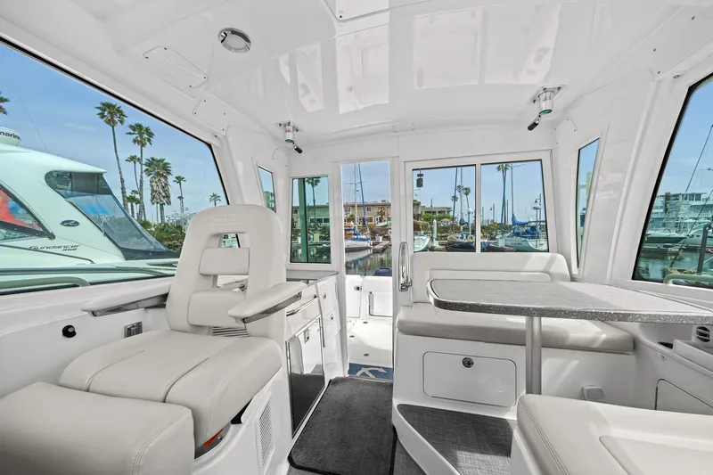  Yacht Photos Pics Interior of 2017 Boston Whaler 345 Conquest Pilothouse with white seating and marina view.