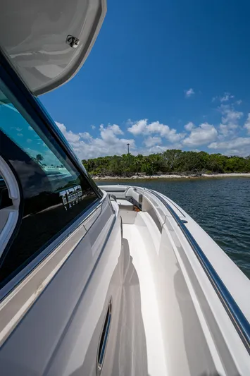 Let It Ride Yacht Photos Pics 2024 Tiara Yachts 38 LS cruising near a scenic shoreline under a clear blue sky.