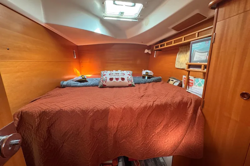 Wayward Sun Yacht Photos Pics Cozy cabin interior of 2000 Lagoon 380 catamaran with wooden finish and comfortable bedding.