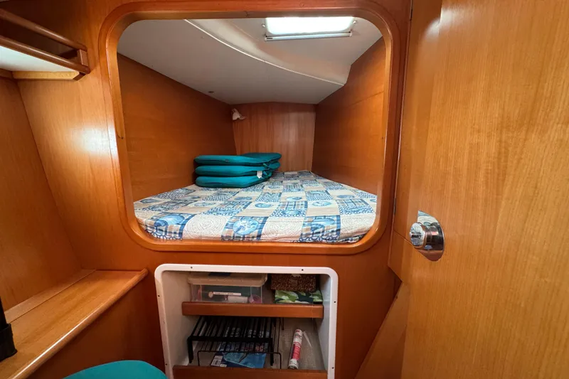 Wayward Sun Yacht Photos Pics Cozy cabin interior of 2000 Lagoon 380 catamaran with wooden finish and patterned bedding.