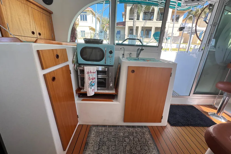 Wayward Sun Yacht Photos Pics Interior of 2000 Lagoon 380 catamaran with kitchenette, featuring wood cabinets and retro appliances.