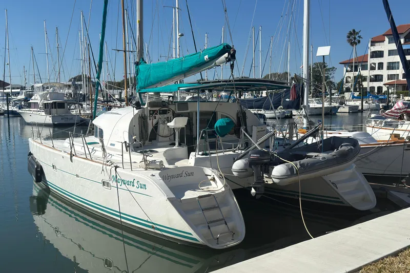 Wayward Sun Yacht Photos Pics Lagoon 380 catamaran from 2000 docked in a marina, surrounded by other boats.