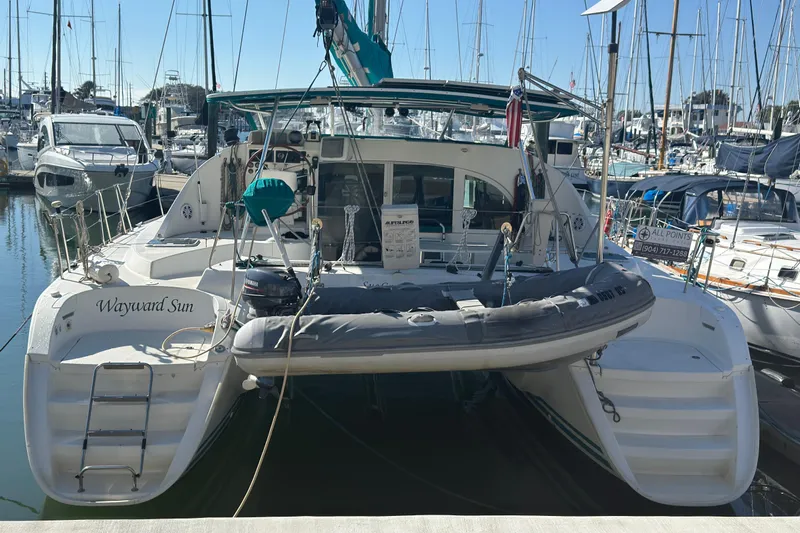 Wayward Sun Yacht Photos Pics Lagoon 380 catamaran from 2000 docked at a marina, surrounded by other boats.