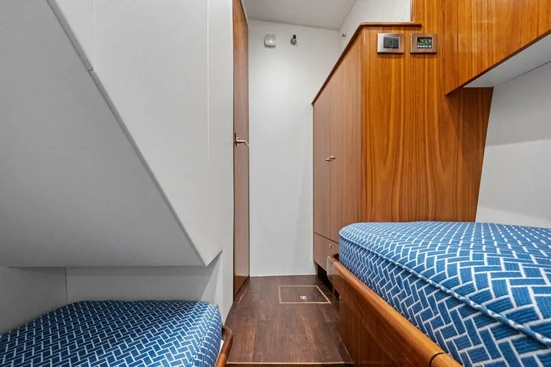Galati Yacht Sales Trade Yacht Photos Pics Interior of 2025 Viking 58 Convertible yacht with wooden cabinetry and blue-patterned bedding.