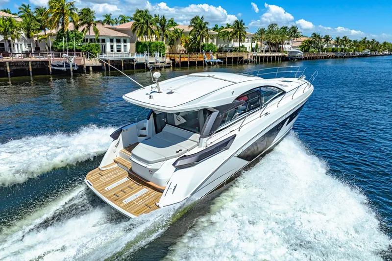  Yacht Photos Pics 2024 Beneteau Gran Turismo 45 yacht cruising on a sunny waterfront with palm trees.