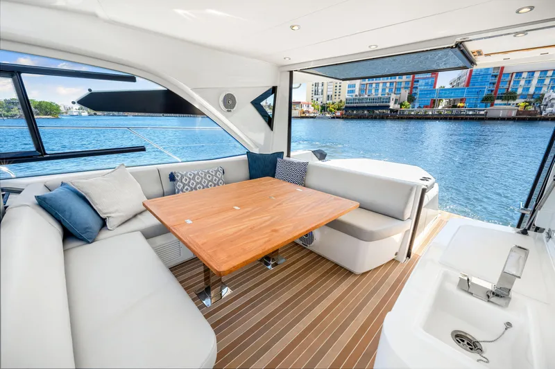  Yacht Photos Pics 2024 Beneteau Gran Turismo 45 yacht interior with elegant seating and wooden table by the water.