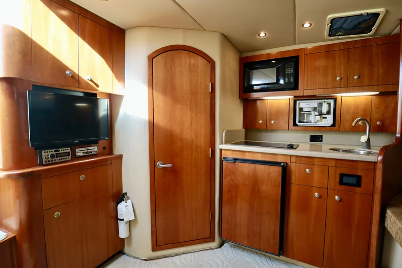  Yacht Photos Pics 2006 Rampage 33 Express yacht interior with kitchenette, TV, and wooden cabinetry.