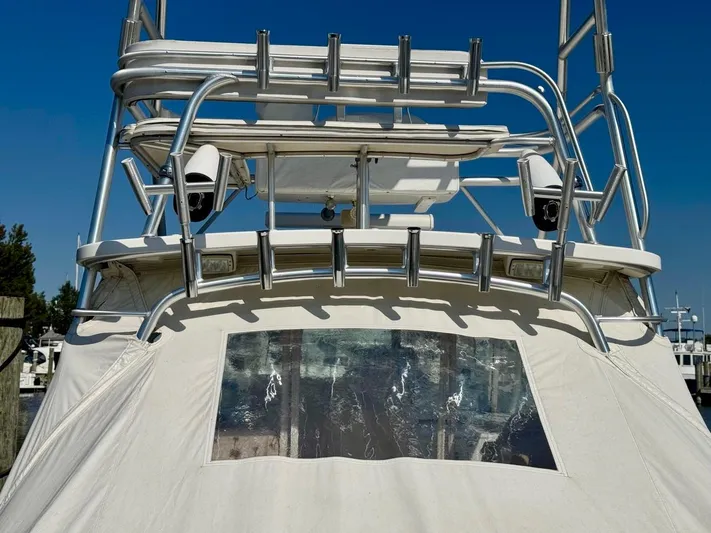  Yacht Photos Pics 2006 Rampage 33 Express boat with tower and canvas cover, docked under clear blue sky.