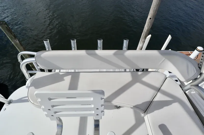  Yacht Photos Pics 2006 Rampage 33 Express boat seating area with rod holders, docked by the water.