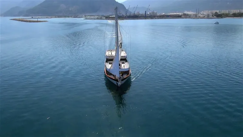 My Dream Yacht Photos Pics Sailing yacht Custom Manavgat GT 457 2009 on calm waters with mountainous backdrop.