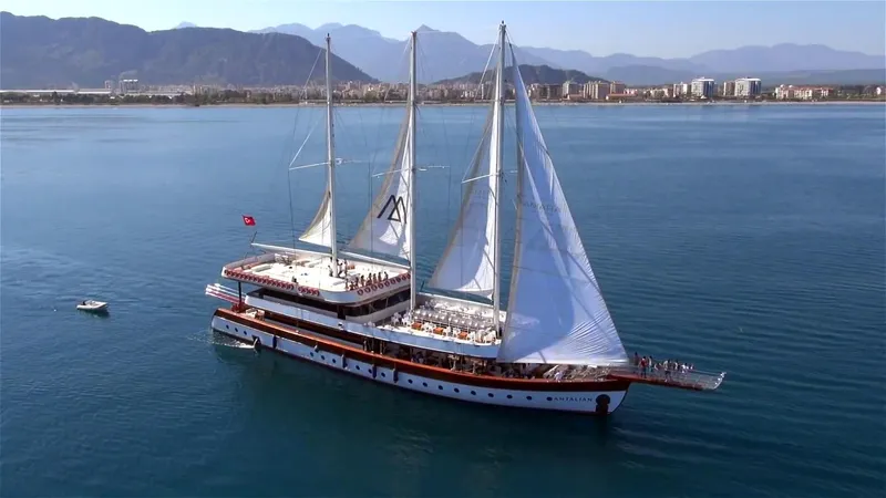My Dream Yacht Photos Pics Large sailing yacht Manavgat GT 457 cruising near coastal city with mountains in the background.