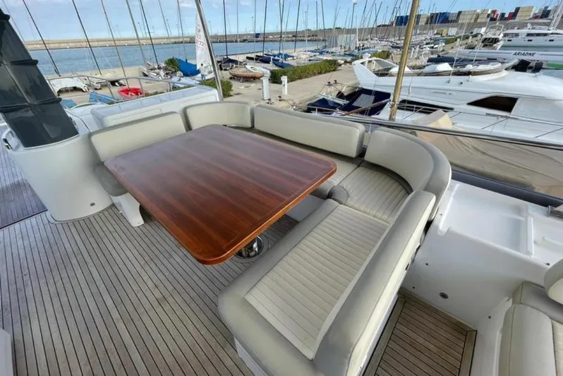  Yacht Photos Pics Luxurious seating area on 2019 Azimut Magellano 66 yacht with wooden table and marina view.