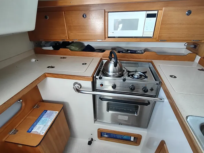 Bluebird Yacht Photos Pics Galley kitchen in 2002 Catalina 36 MkII sailboat with stove, microwave, and wooden cabinetry.
