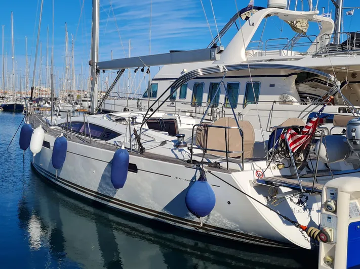  Yacht Photos Pics 2015 Jeanneau 57 yacht docked at marina with blue fenders and American flag.