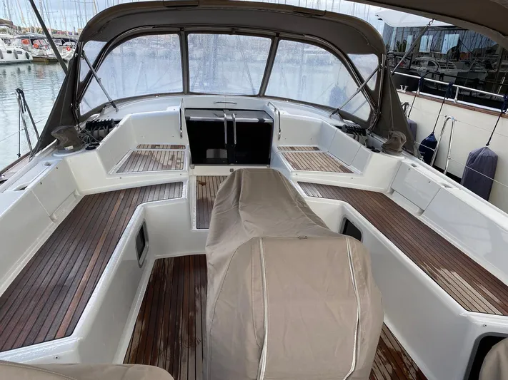  Yacht Photos Pics 2015 Jeanneau 57 yacht cockpit with covered seating and wooden flooring in a marina.