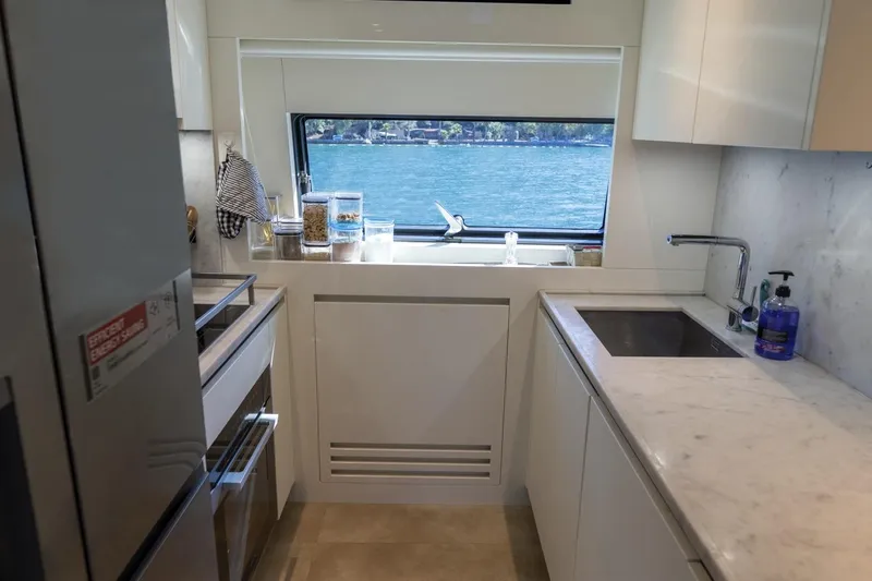  Yacht Photos Pics Modern kitchen interior of 2023 Sanlorenzo SX76 yacht with marble countertops and scenic window view.