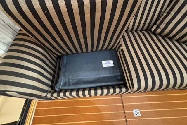 Aqua Billy Yacht Photos Pics Striped couch with hidden compartment, containing a black item, on wooden floor.
