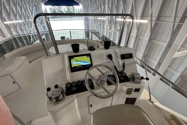 Aqua Billy Yacht Photos Pics Boat cockpit with steering wheel, navigation screen, and controls in a covered dock.