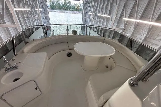 Aqua Billy Yacht Photos Pics Luxurious boat interior with curved seating and table, docked in a covered marina.