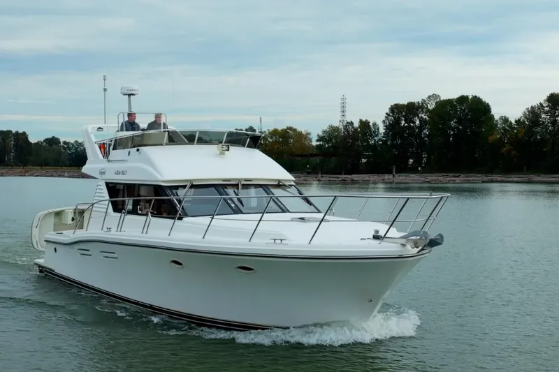 Aqua Billy Yacht Photos Pics A luxury yacht cruising on a calm river with lush green trees in the background.
