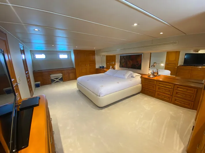 Mi Amor Yacht Photos Pics Luxurious bedroom interior on 1984 DeFever 120 yacht, featuring elegant wood furnishings and ambient lighting.