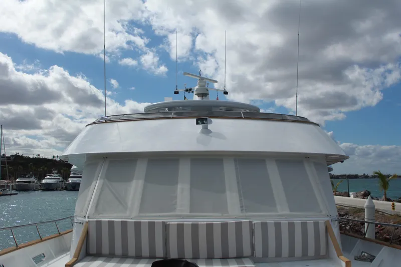 Mi Amor Yacht Photos Pics 1984 DeFever 120 yacht with striped seating, docked under a partly cloudy sky.