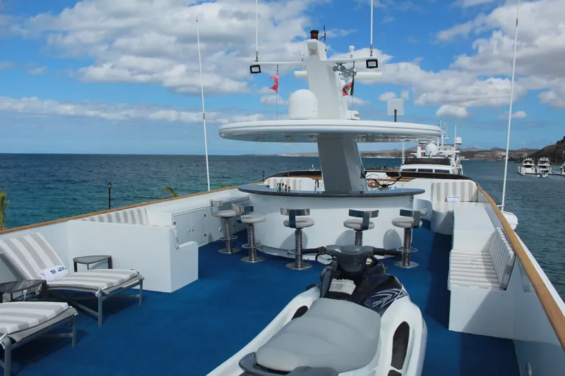 Mi Amor Yacht Photos Pics Luxurious 1984 DeFever 120 yacht deck with bar, seating, and jet ski, overlooking ocean.