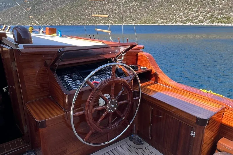  Yacht Photos Pics Wooden helm of Custom Sailing Yacht Ocean Pure, 1993, overlooking serene blue waters.