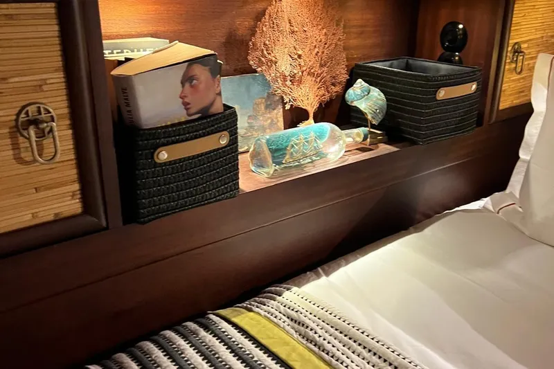  Yacht Photos Pics Cozy yacht cabin with books, decorative items, and a ship in a bottle on a wooden shelf.