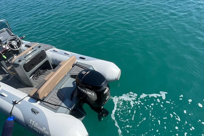  Yacht Photos Pics Inflatable boat with Suzuki outboard motor on turquoise water, part of 1993 Sailing Yacht Ocean Pure.