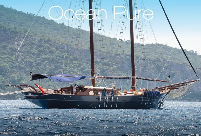  Yacht Photos Pics Sailing Yacht Ocean Pure, 1993, cruising on serene waters with lush green hills in the background.