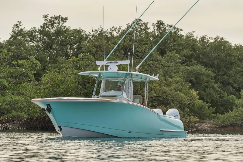  Yacht Photos Pics 2025 Mag Bay 33 boat on water near lush green trees.