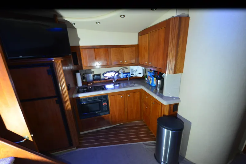 Seeking Sara Yacht Photos Pics 2003 Cruisers Yachts 4370 Express kitchen with wooden cabinets and modern appliances.