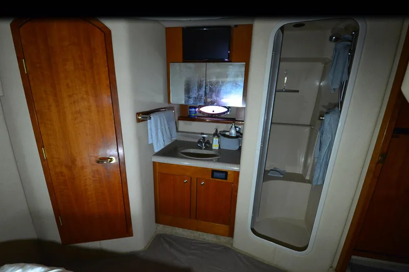Seeking Sara Yacht Photos Pics 2003 Cruisers Yachts 4370 Express bathroom with shower, sink, and wooden cabinetry.