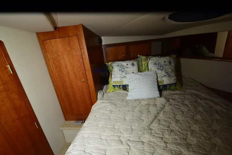 Seeking Sara Yacht Photos Pics Cozy bedroom interior of 2003 Cruisers Yachts 4370 Express with wooden cabinetry and plush bedding.
