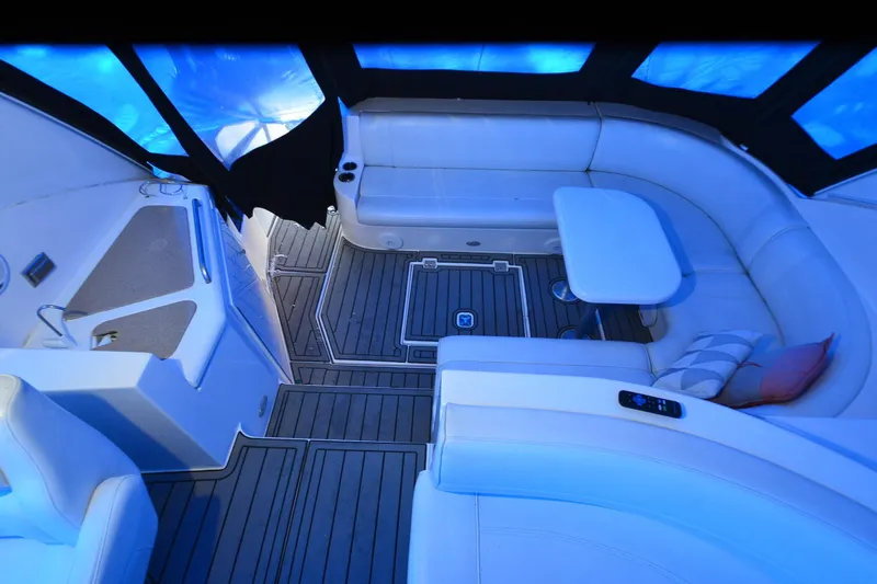 Seeking Sara Yacht Photos Pics 2003 Cruisers Yachts 4370 Express interior with white seating and table, under blue lighting.