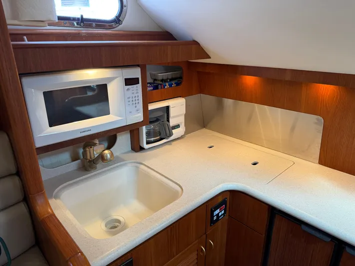 Cyette Yacht Photos Pics 2003 Pursuit 3800 Express yacht kitchen with microwave, sink, and wooden cabinetry.
