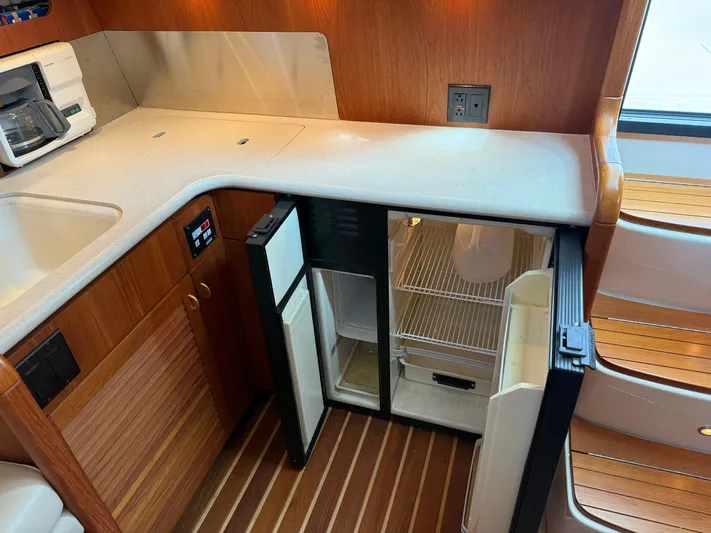 Cyette Yacht Photos Pics 2003 Pursuit 3800 Express yacht kitchen with open fridge, wooden cabinetry, and countertop.