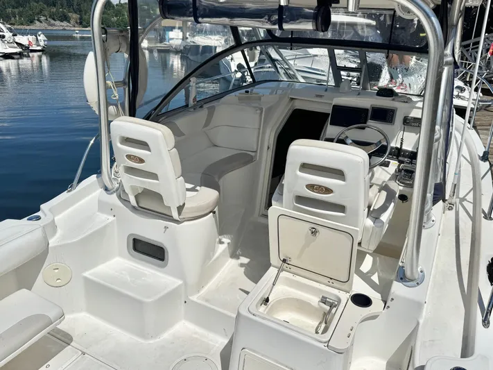  Yacht Photos Pics 2008 Boston Whaler 285 Conquest boat interior with helm and seating area, docked by the water.