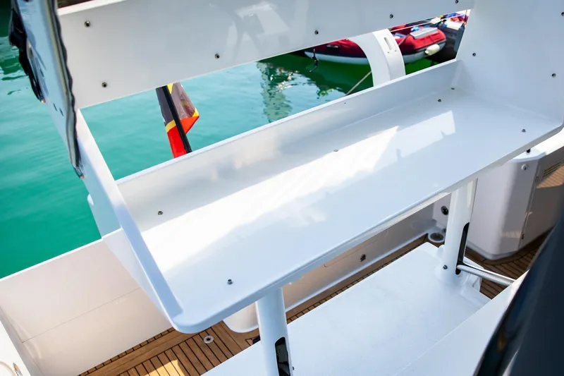  Yacht Photos Pics 2022 HH55 Catamaran deck with white seating and wooden flooring, docked by the water.